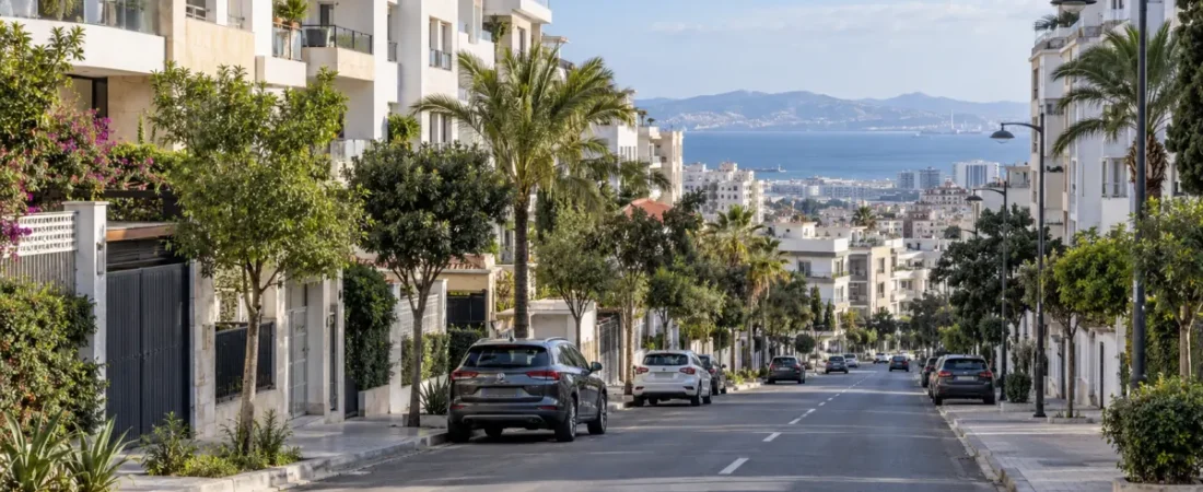 Residential avenue in Tangier with apartment buildings, greenery and the Strait in the distance